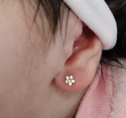 Orelha de bebê com brinco de florzinha após furo humanizado em Videira