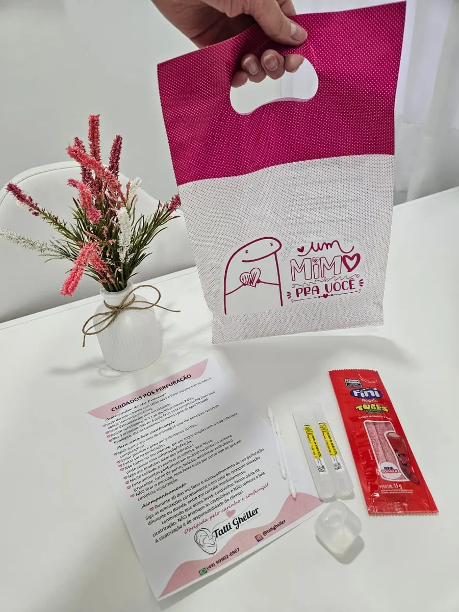 Kit Mimo pra você: sacola rosa, guia de cuidados pós-perfuração e itens de higiene