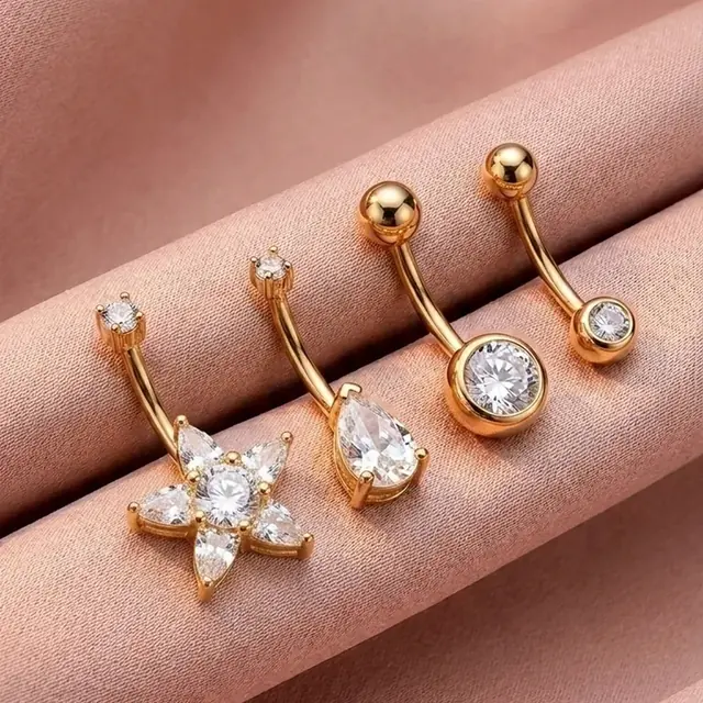 Conjunto de piercings dourados com flor e pedras sobre cetim rosé