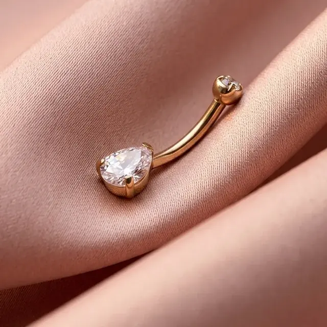 Piercing dourado com cristal em gota sobre cetim rosé